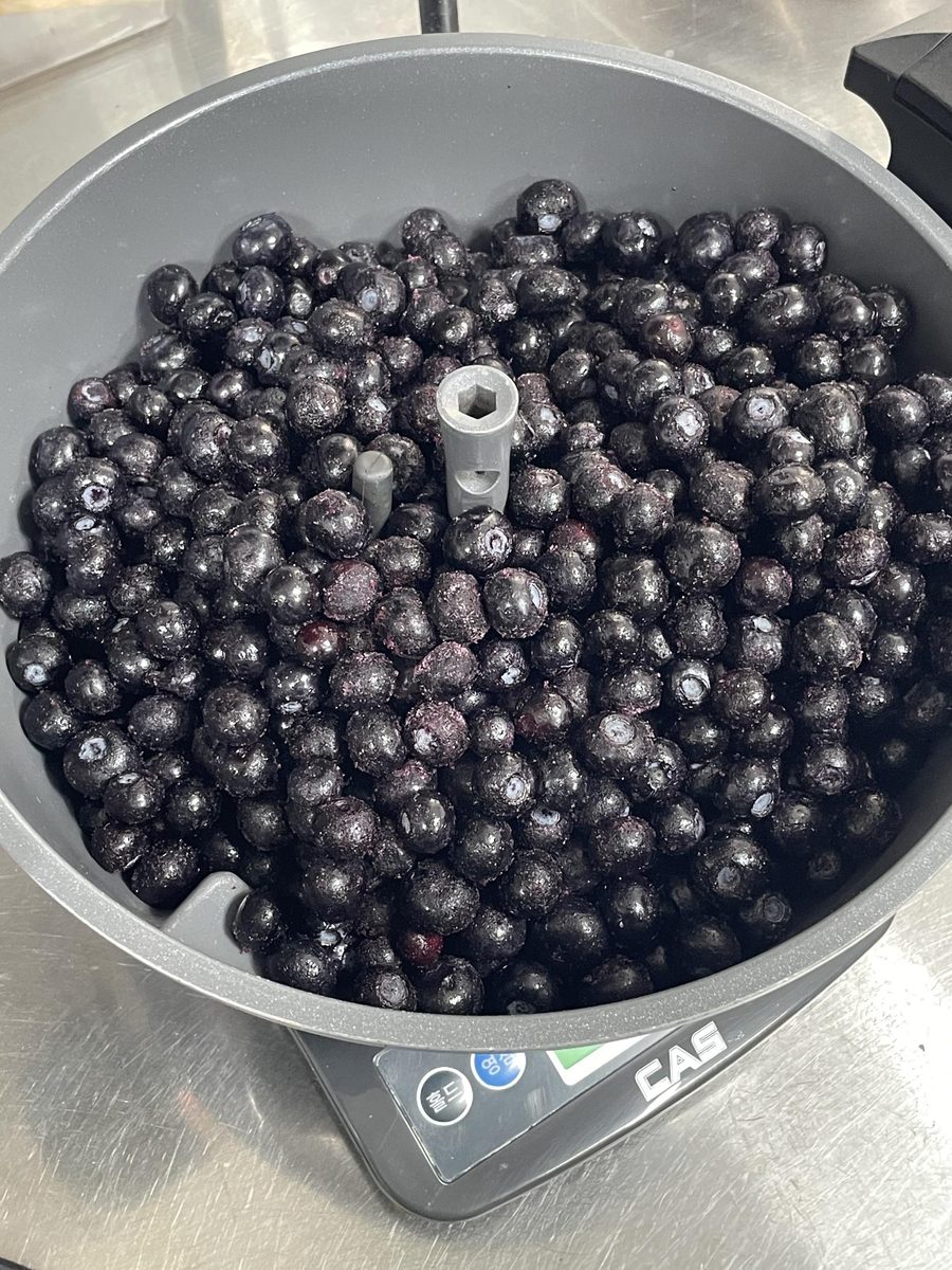 A bowl of whole blueberries on a kitchen scale