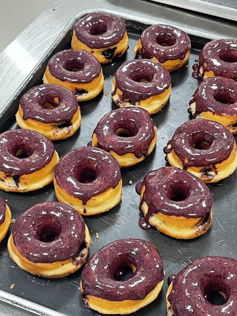 A tray of donuts with glossy blueberry glaze